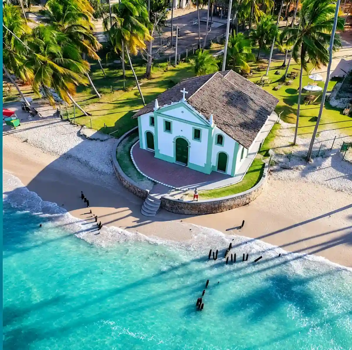 Capela de São Benedito na areia da Praia dos Carneiros, cercada de coqueiros