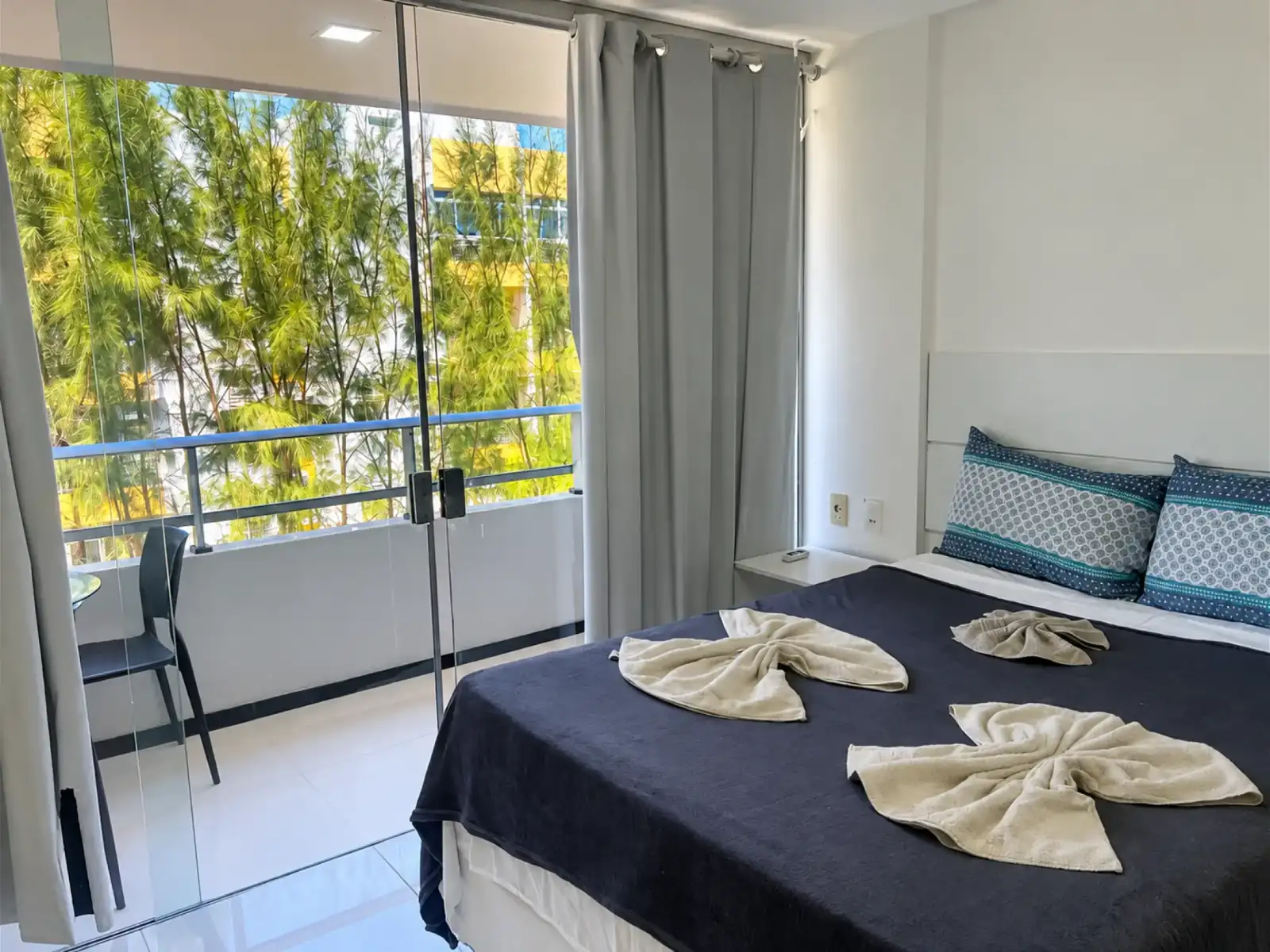 Quarto do apartamento com cama de casal e portas de vidro para a varanda