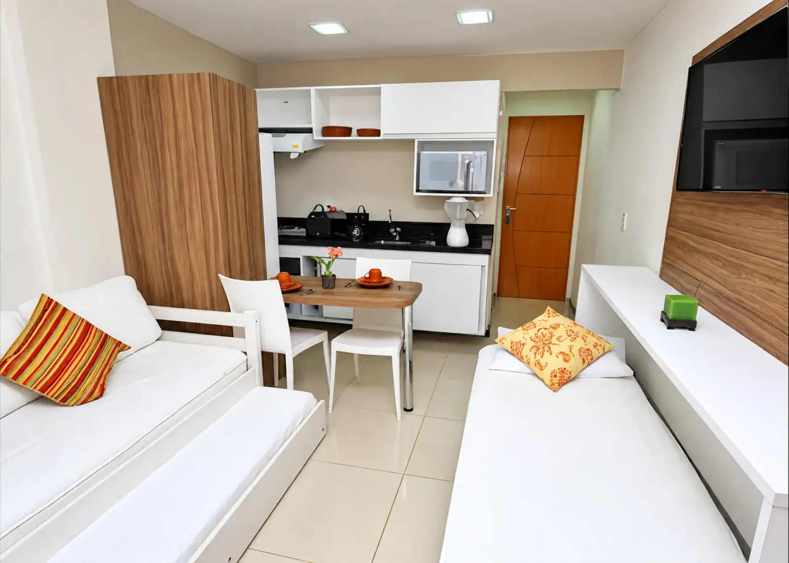 Sala do apartamento com sofá-cama, mesa de jantar e copa equipada